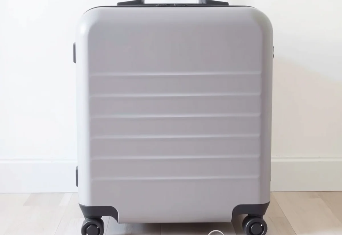 Suitcase beside car keys A grey carry-on suitcase standing on a light wooden floor